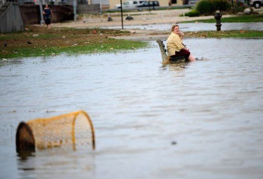 Una mujer y un niño permanecen sentados en un banco en una zona inundada de Rockway Beach, en Nueva York, al paso del huracán Irene el domingo 28 de agosto.