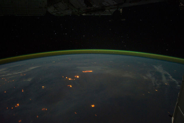 Los incendios agrícolas, quema en el continente de Australia, con el humo de plumas apenas visible en el cielo nocturno, en esta imagen tomada por los astronautas en la Estación Espacial Internacional (ISS) con una cámara digital. Un halo de oro y verde de la atmósfera resplandece sobre el horizonte en la distancia. Foto tomada el 17 de septiembre. REUTERS / NASA 