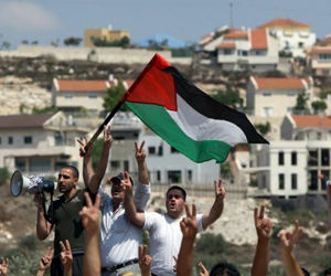 Manifestantes palestinos ondean su bandera durante una protesta por el corte de una carretera por colonos israelíes del asentamiento de Kadumim, en el pueblo de Kfar Kadum en Cisjordania. Foto: AFP