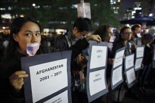 Manifestantes con una bandera de los EE.UU. pegada a la boca, sostienen carteles en el Zuccotti Park, cerca de Wall Street en Nueva York. Foto: Reuters