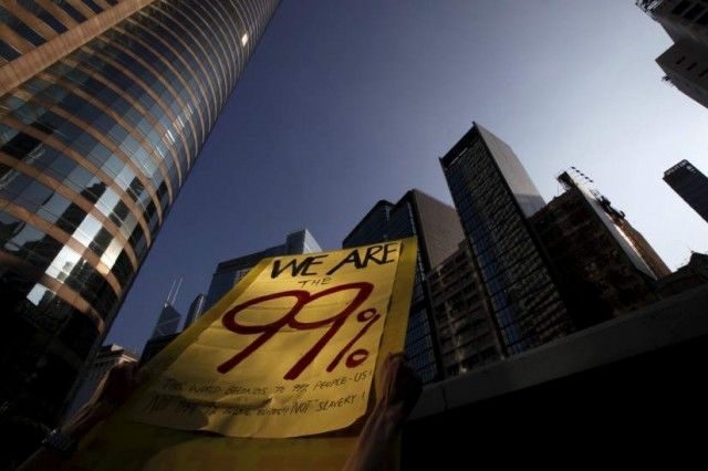 Un 'indignado' sostiene una pancarta con el mensaje "somos el 99%" en pleno distrito financiero de Hong Kong. (Tyrone Siu / REUTERS)