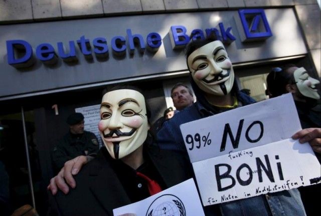 Los 'indignados' de Colonia se manifiestan frente al banco Deutsche Bank, caracterizados con las máscaras de 'V de Vendetta'. (Wolfgang Rattay / REUTERS)